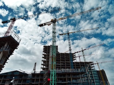  Someone looking up at a crane all pointing to the right with scaffolding around the building in a construction site managed by a contractor. 
