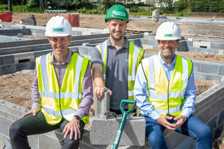 Three construction workers sat on building foundations
