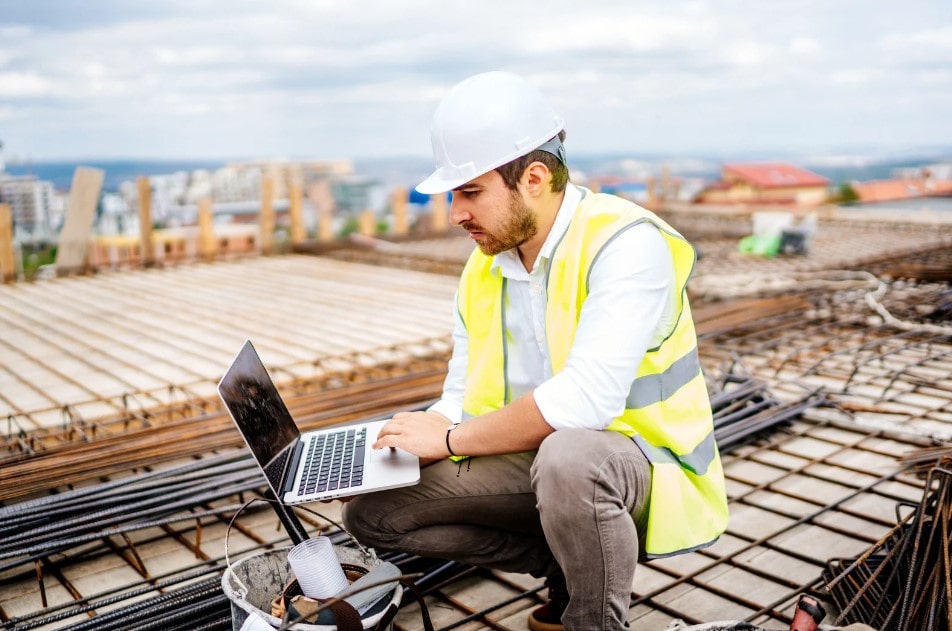 A construction worker using the software app, Whatsapp, on a mobile phone for construction management.