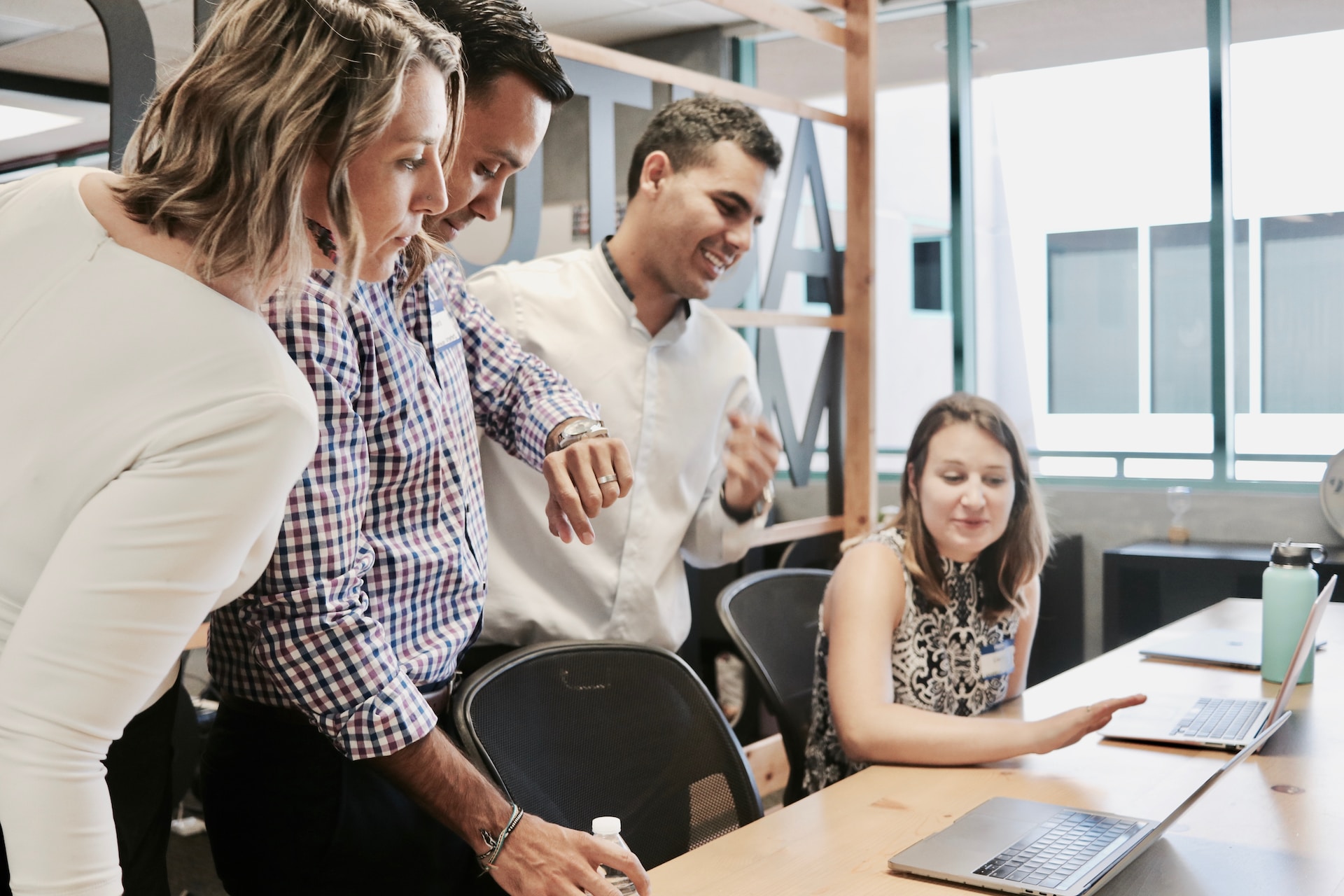 Two women and men discussing how Cube’s Milestone software is streamlining construction projects in front of a laptop. 